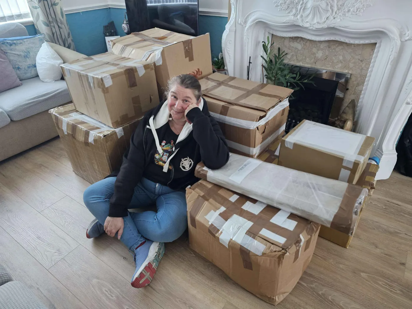 A UCoR organiser sitting on the floor surrounded by a pile of taped-up cardboard boxes of auction stock
